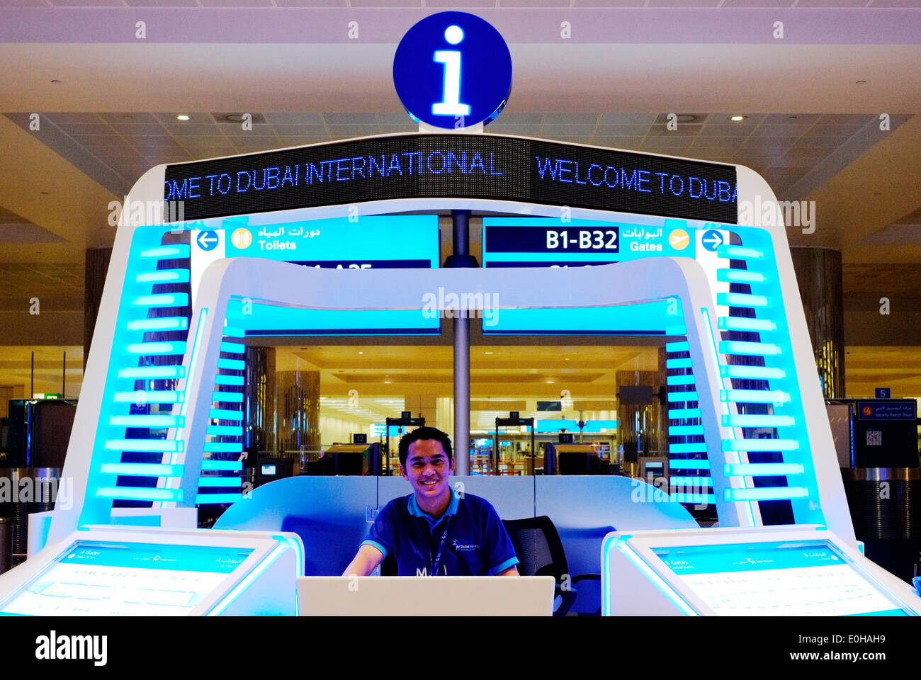 Gentile lavoratore di sesso maschile su un banco informazioni nelle prime ore del mattino all'aeroporto internazionale di Dubai Foto Stock