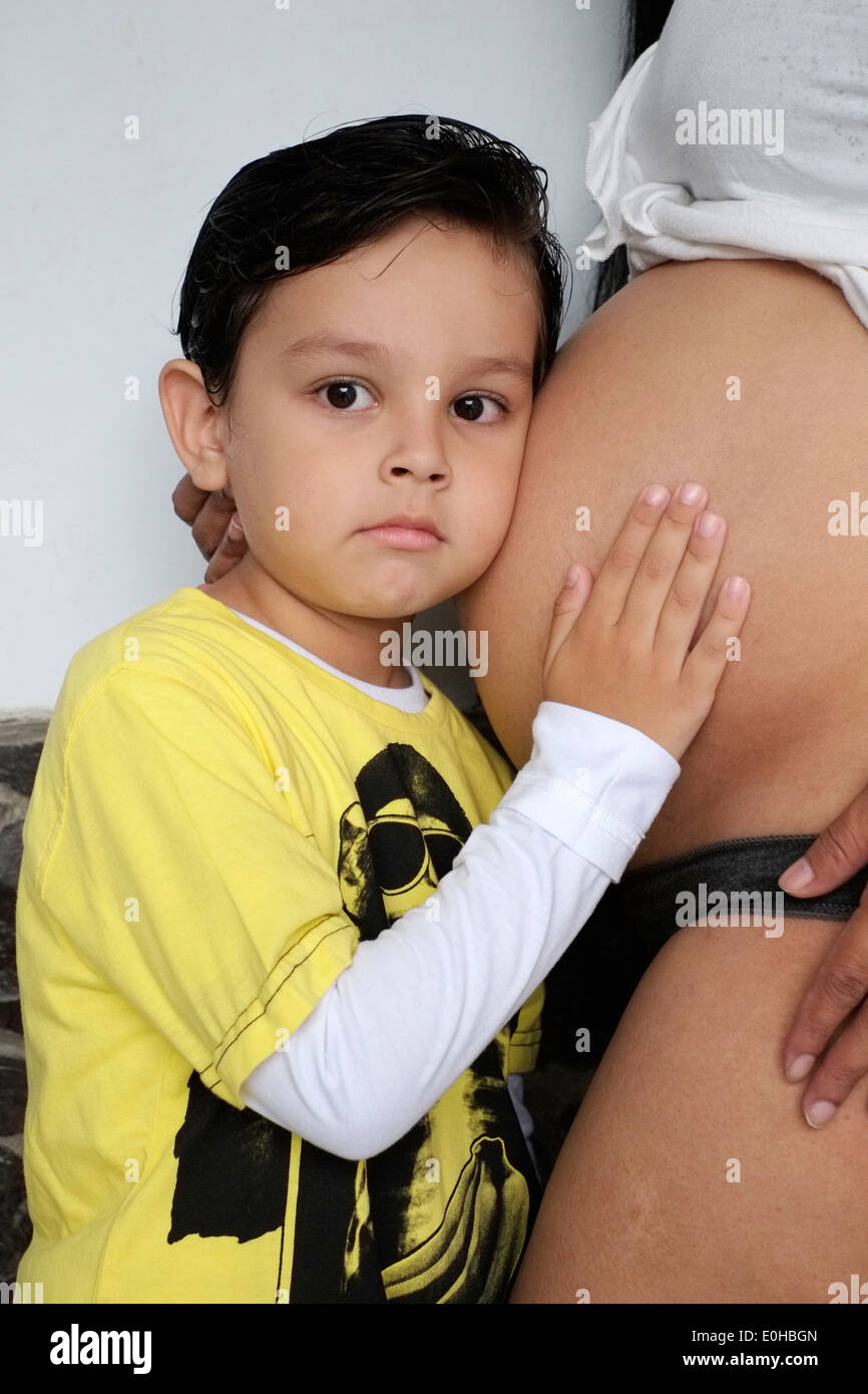 Ragazzo con la mano sulle madri incinte ascolto dello stomaco e la sensazione di movimento del bambino Foto Stock