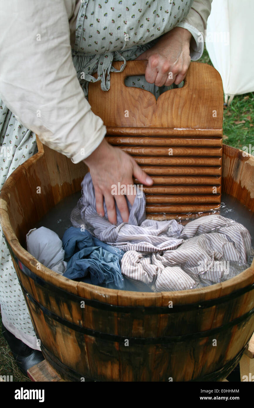 Una dimostrazione di come il bucato veniva fatto ai tempi coloniali in una  vasca di legno con un lavaggio in legno e scheda di lavoro di mano Foto  stock - Alamy