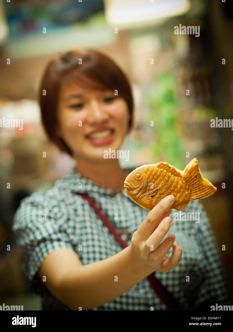 Una ragazza felice tiene fino a Taiyaki, un giapponese a forma di pesce farcita con pasta di fagiolo rossa, dalla Takashimaya e store a Singapore Foto Stock