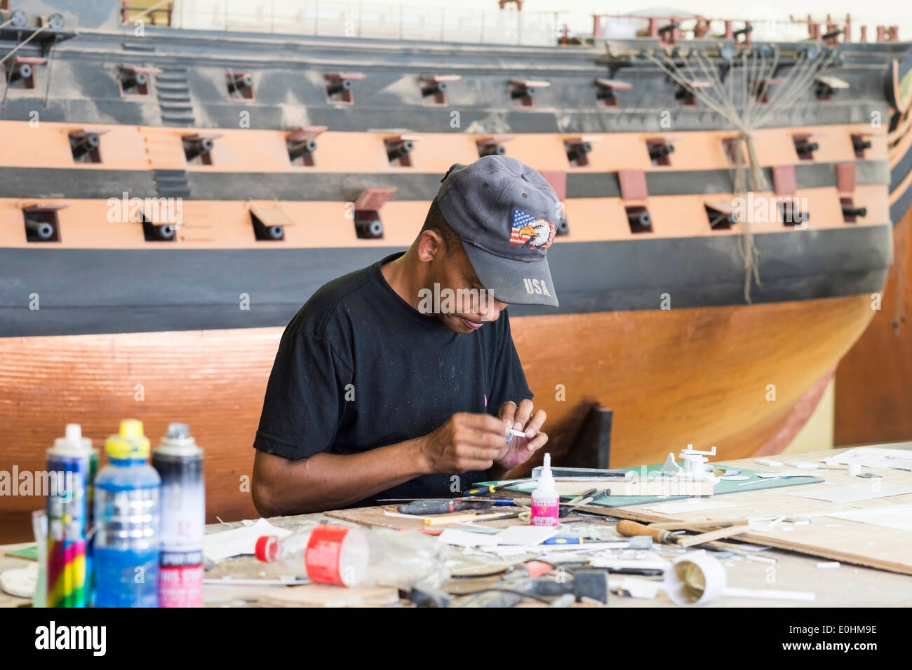 L'uomo l'incollaggio di parti di piccole dimensioni sul lavoro al modello di costruttori di navi, cantieri navali, Mosselbay, Sud Africa Foto Stock