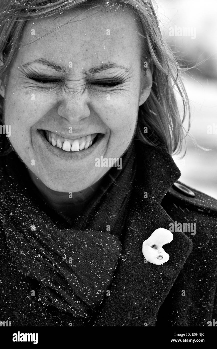Giovane donna sorridente mentre la neve è caduta qui intorno, Leyton, London, Regno Unito Foto Stock