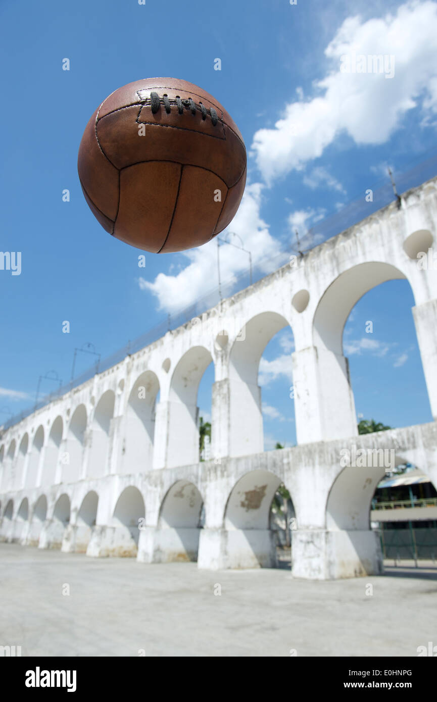 Marrone Vintage palla calcio calcio volare nel cielo a Arcos da Lapa archi di Rio de Janeiro in Brasile Foto Stock