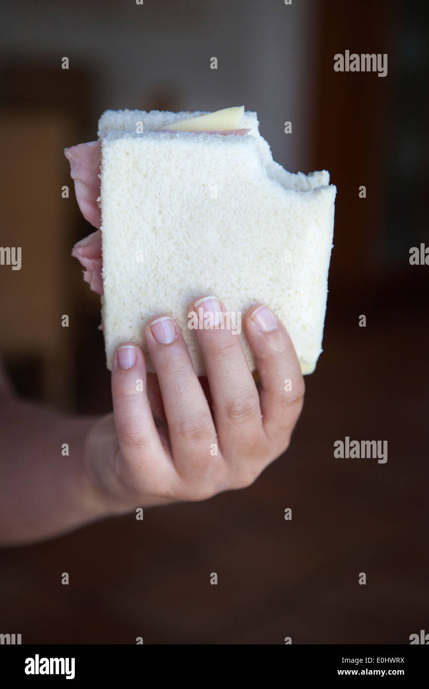 Un ragazzo con le mani in mano mostra il suo prosciutto e formaggio panino Foto Stock