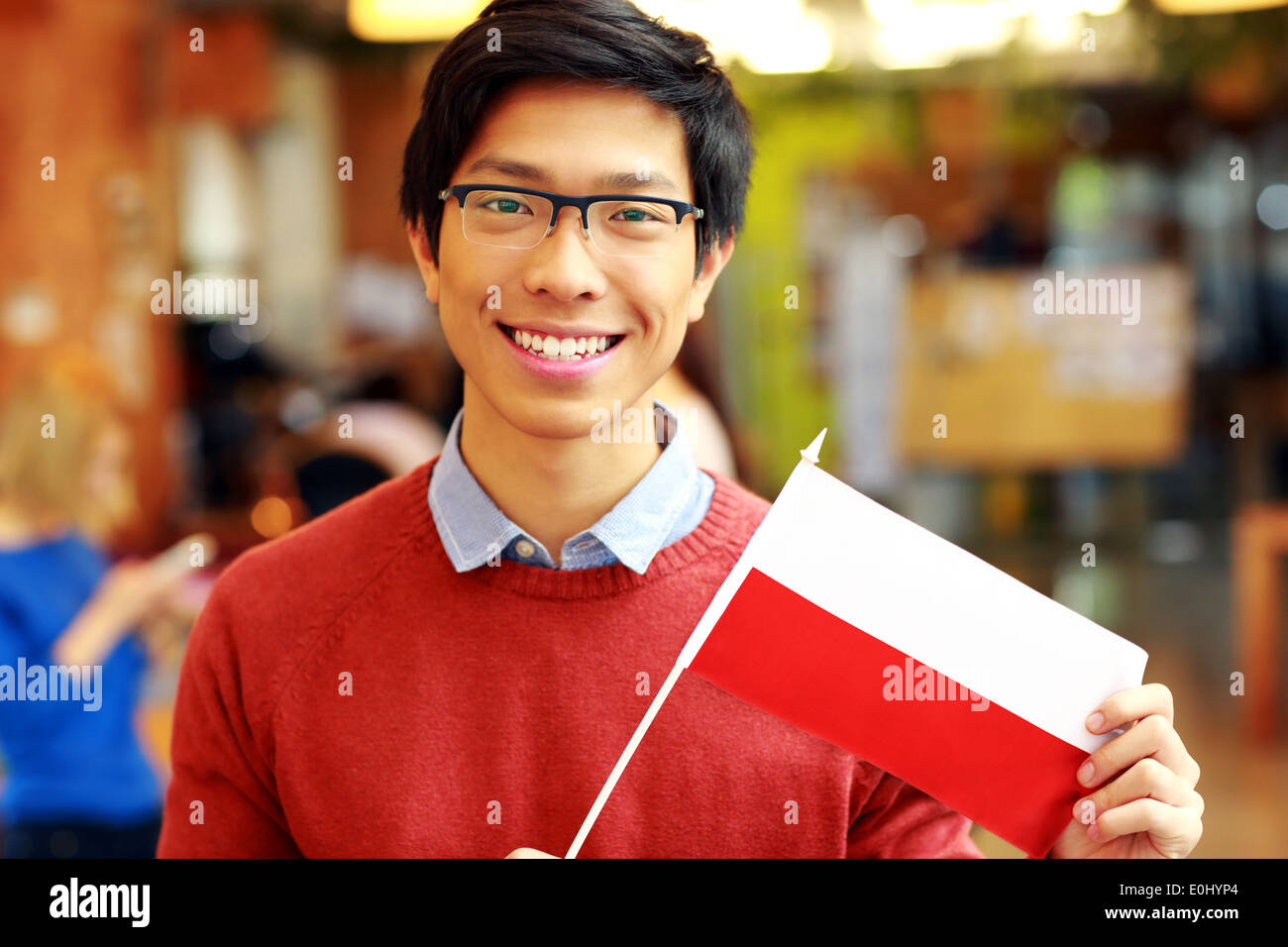 Sorridente ragazzo asiatico in bicchieri holding bandiera della Polonia Foto Stock