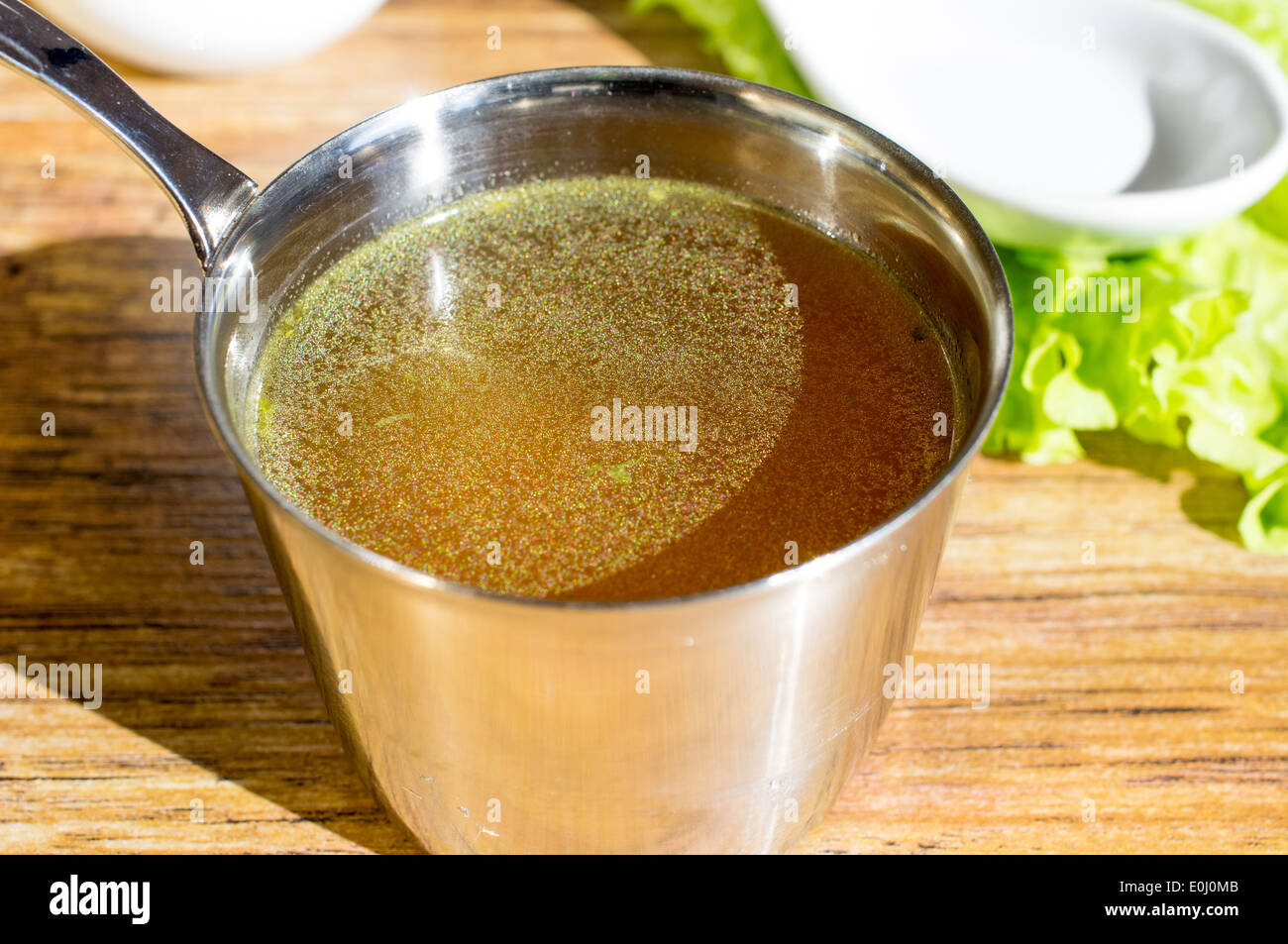 Il brodo di pollo, bouillon, minestra chiaro in una tazza accanto alle erbe fresche. Foto Stock