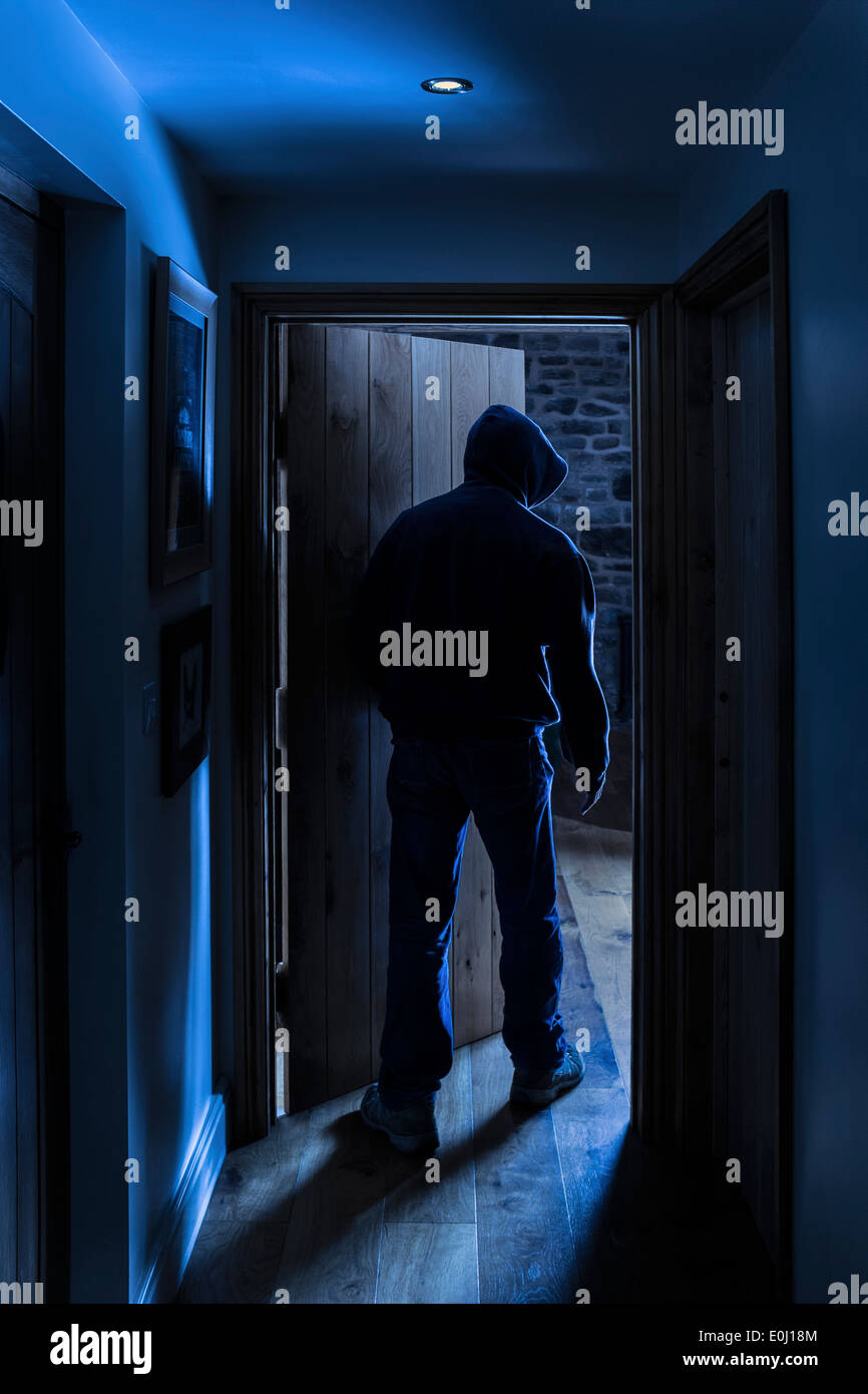 Un anonimo maschio con cappuccio di entrare in una stanza. Foto Stock