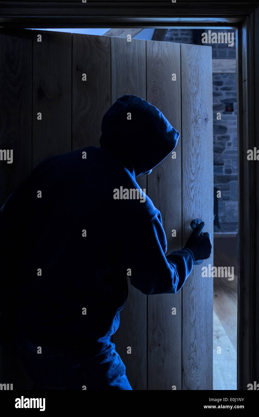Un anonimo maschio con cappuccio di entrare in una stanza. Foto Stock