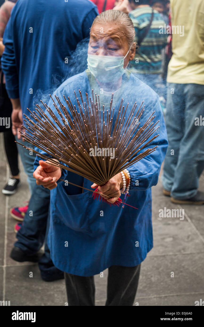 Senior donna holding bastoncini di incenso a Hsing Tian Kong in Taiwan Foto Stock