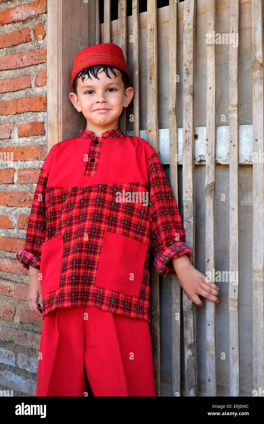 Piccolo scolaro indonesiano orgogliosamente in posa nella sua scuola uniforme in un piccolo villaggio rurale in java Foto Stock