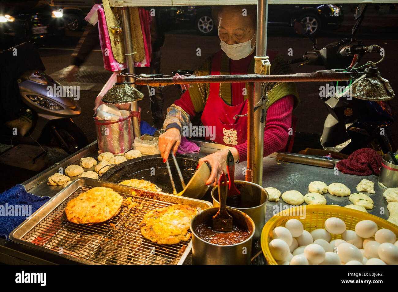 La donna la cottura di cipolla verde frittelle a food stand in Taiwan Foto Stock