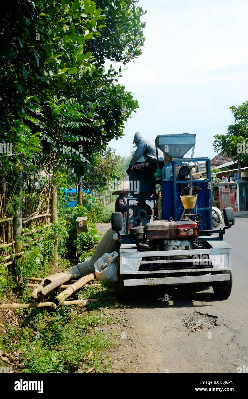 Gli uomini locali su un mobile di riso macchina di vagliatura a vendere riso per gli abitanti di un villaggio in java indonesia Foto Stock