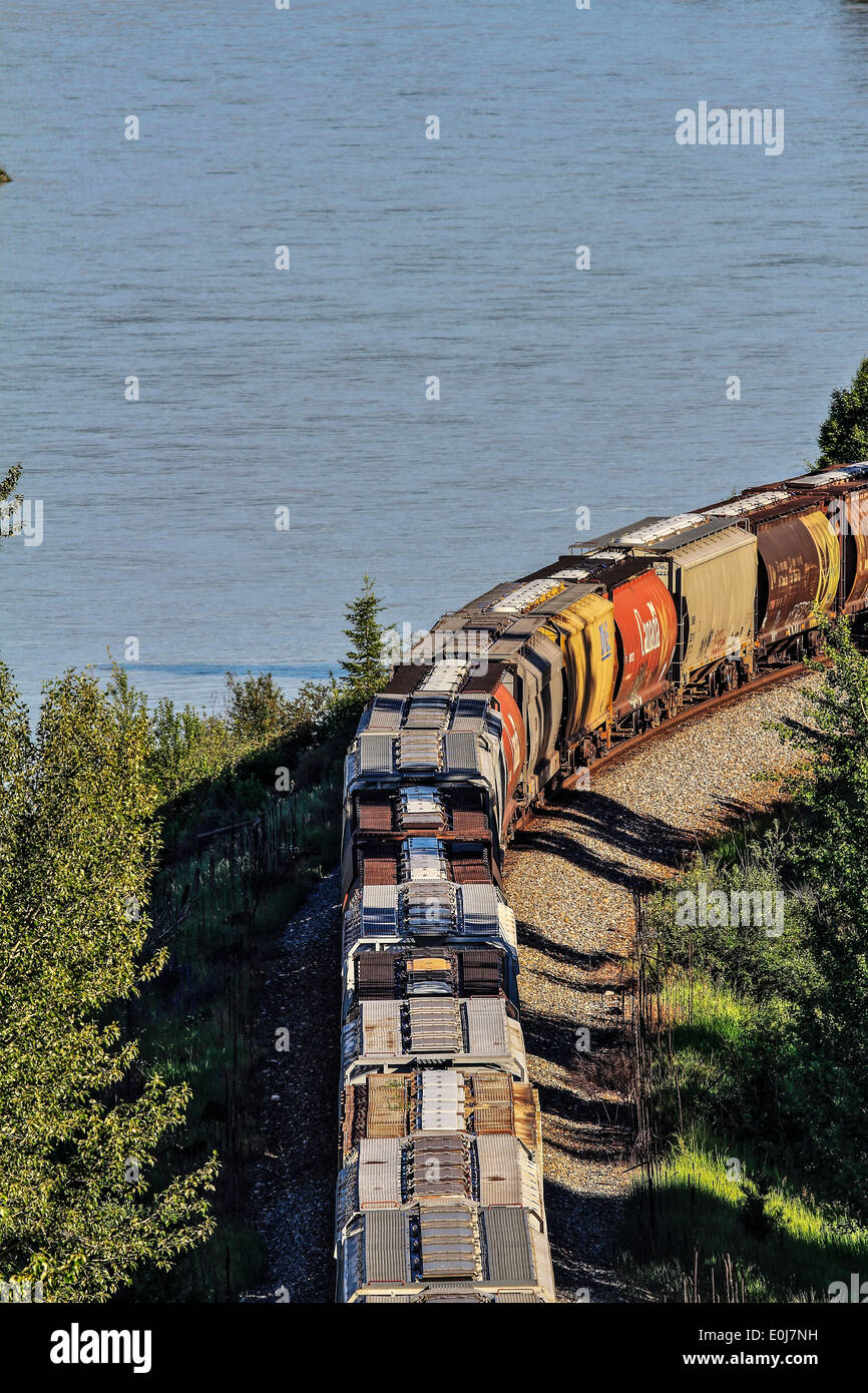 CP convoglio ferroviario, che trasportano merci come si arrotonda la curva accanto al Kootenay River. Cranbrook, British Columbia, Canada. Foto Stock