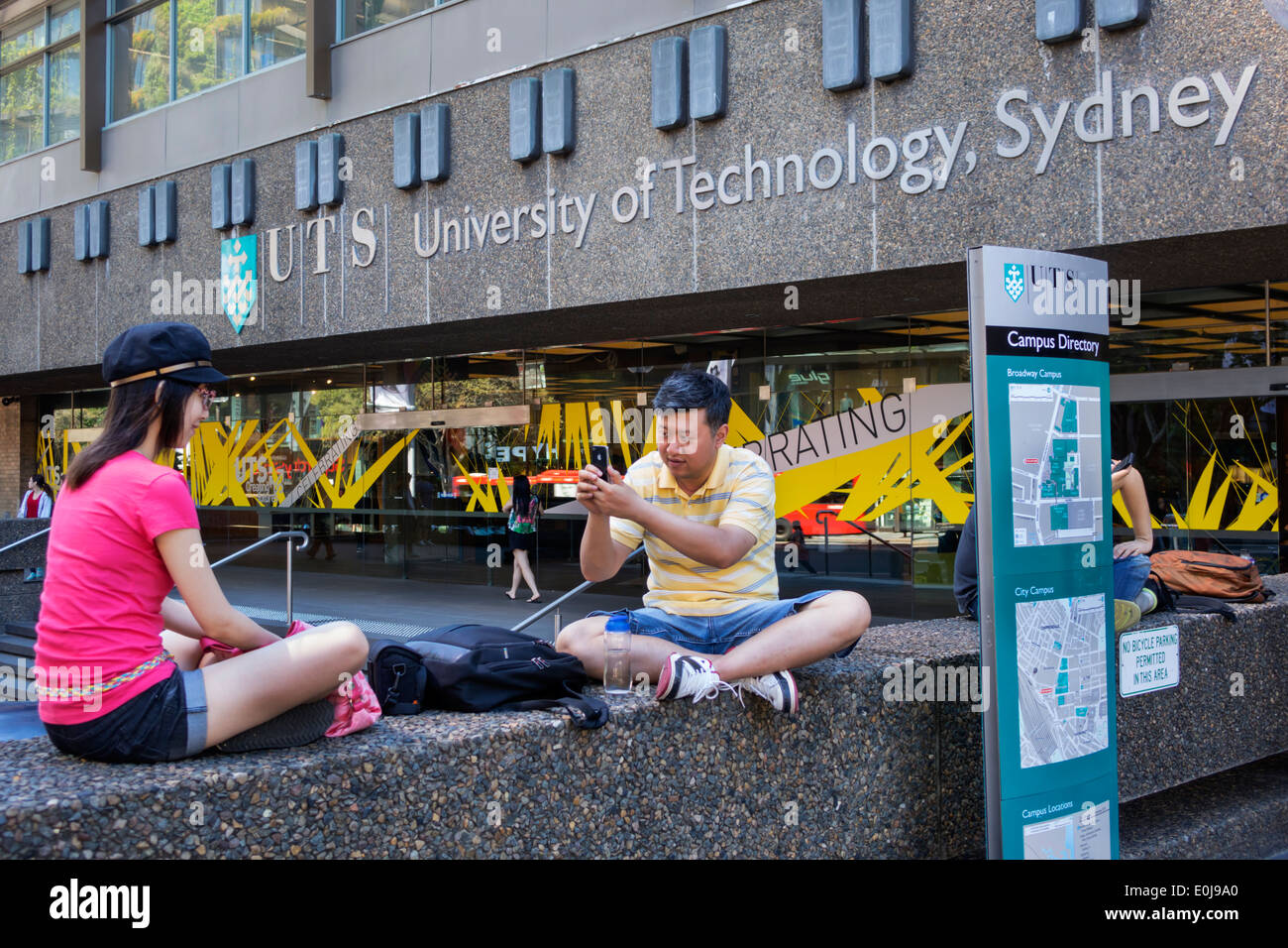 Sydney Australia,UTS,University of Technology Sydney,uomo asiatico maschio,prendendo iPhone,smartphone telefoni cellulari,controllare cercando di leggere SMS Foto Stock