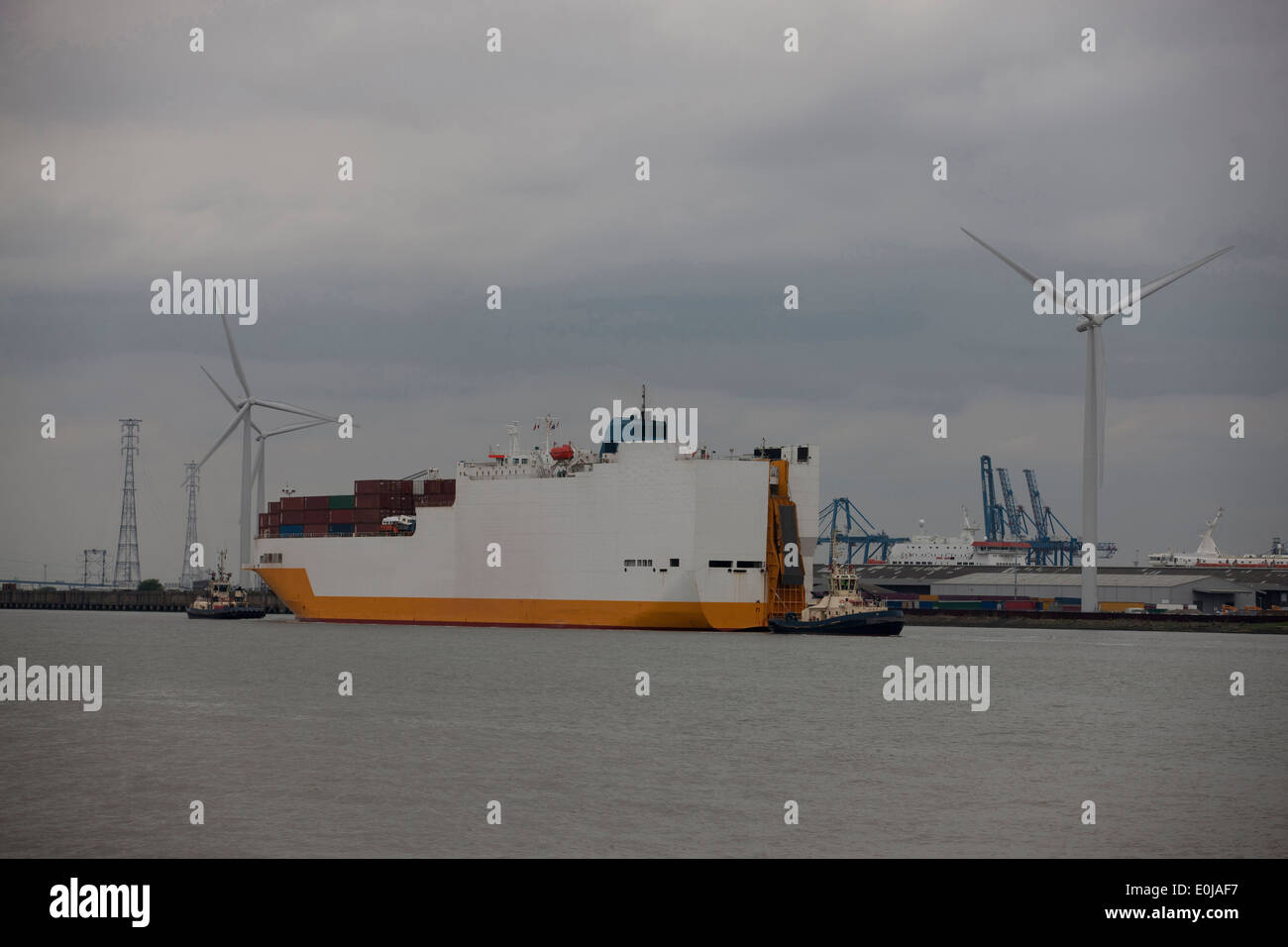 Una nave portacontainer di essere accompagnati al porto da barche rimorchiatore Foto Stock