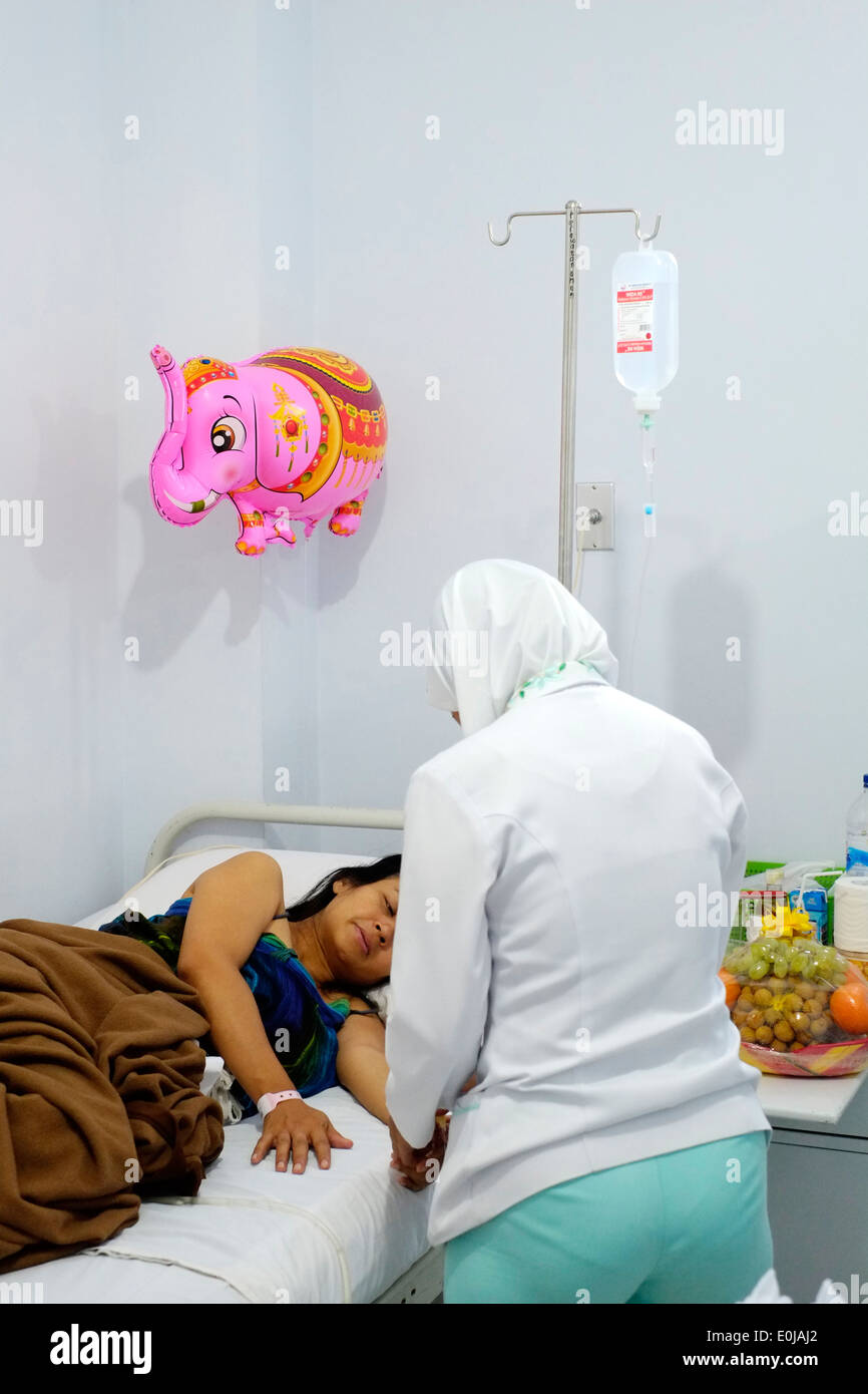 Un infermiere partecipando a un paziente subito dopo il suo taglio cesareo c la sezione funzionamento in un ospedale privato di malang indonesia Foto Stock