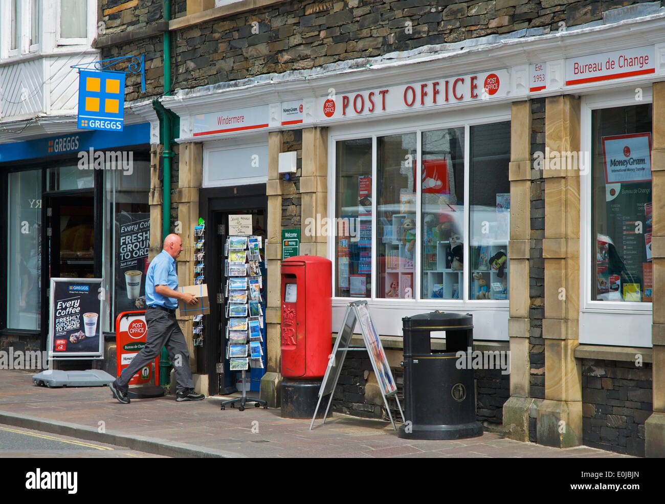 Uomo che porta il pacco in ufficio postale, Cumbria, England Regno Unito Foto Stock