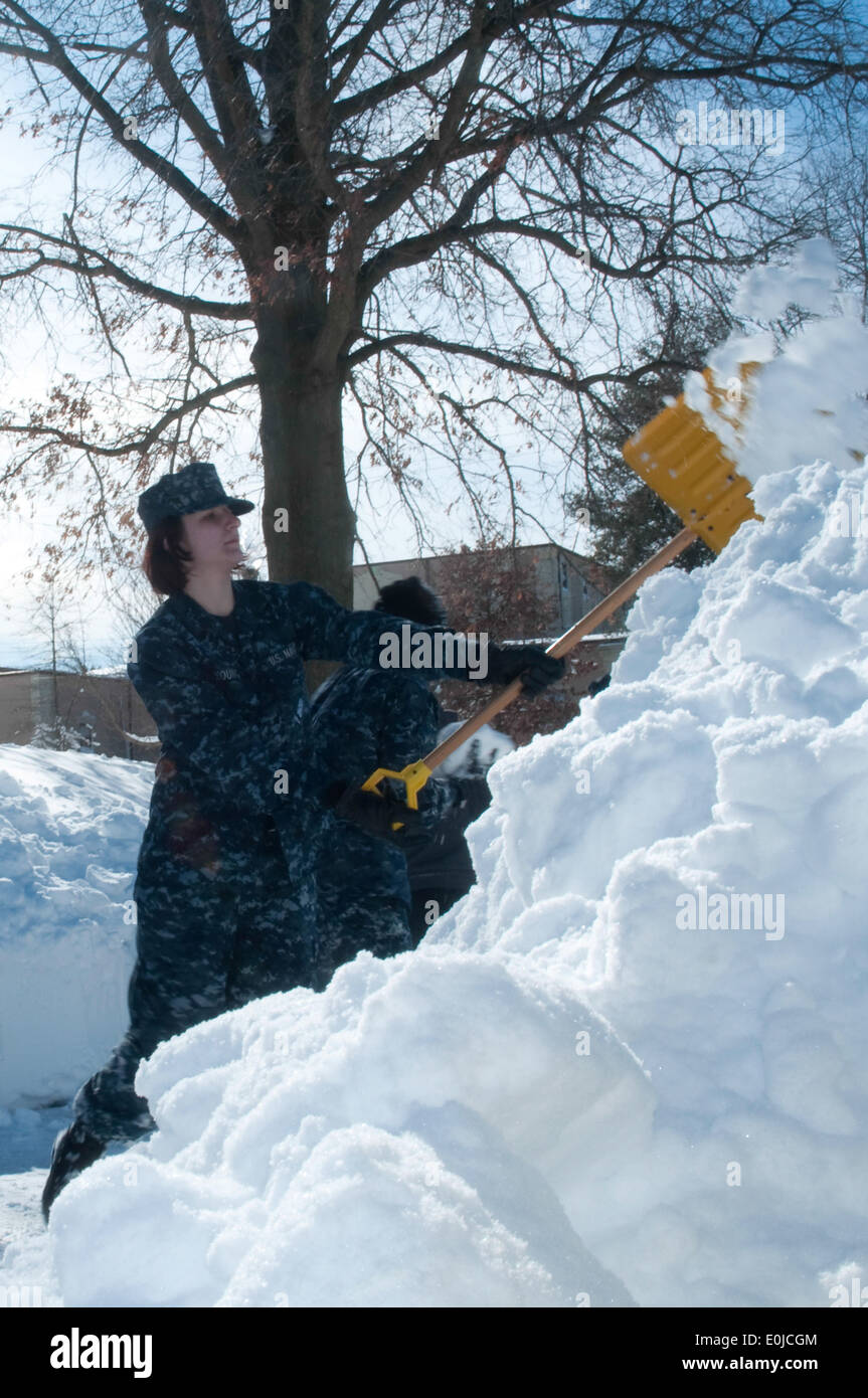 Navy Seaman reclutare Kristina giovane scaglia una shovelful della neve durante la pulizia al centro del servizio di assistenza il distacco ba Foto Stock