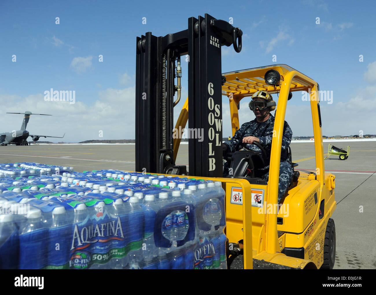 Petty Officer 1. Classe Steven DeMay, aviazione nostromi mate (manipolazione), cale un pallet di bottiglie di acqua verso un MH-53E hel Foto Stock