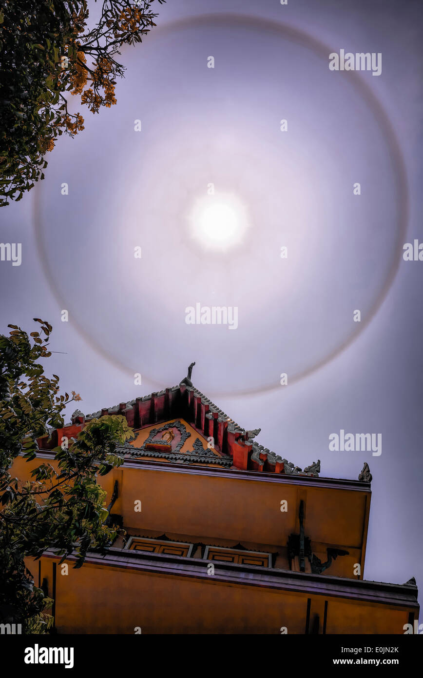 Sun fenomeni di anello 22° grado visto oltre un Thai tempio buddista. Thailandia SUDEST ASIATICO Foto Stock