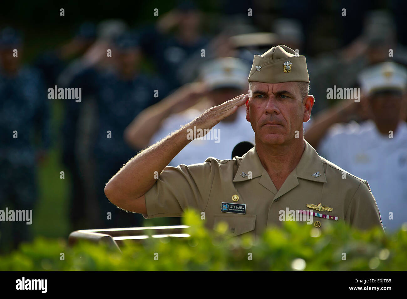 Stati Uniti Navy Capt. Jeffery James, Base comune perla Harbor-Hickam commander, saluta come la bandiera americana viene sollevata per mezzo di un personale Foto Stock