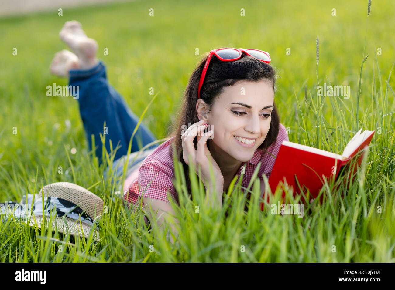 Donna sdraiata con libro nel prato, (modello di rilascio) Foto Stock