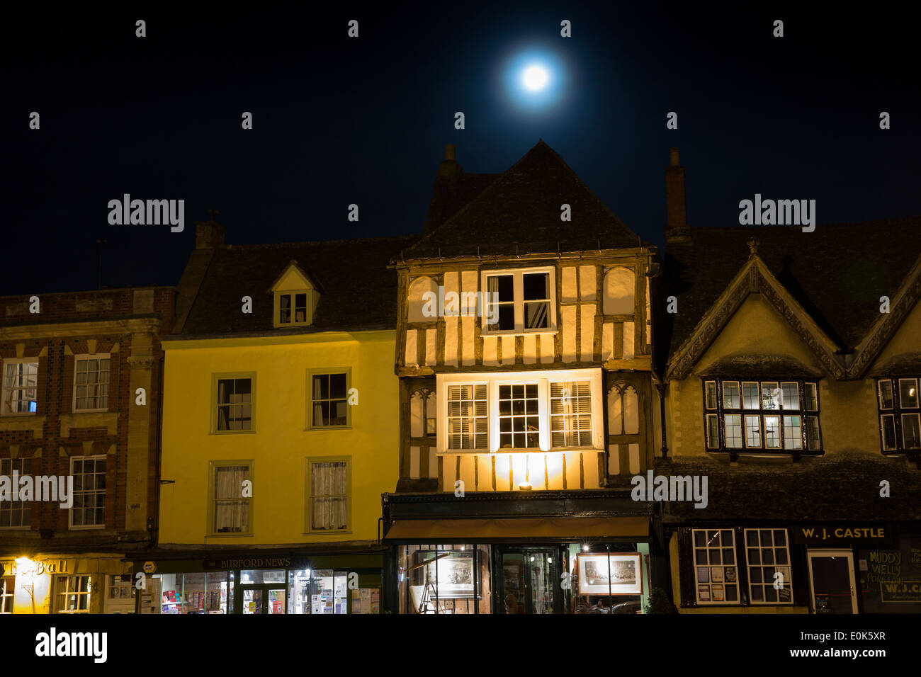 La luna piena risplende sull'architettura medievale lungo Burford High Street di notte, i Cotswolds Foto Stock