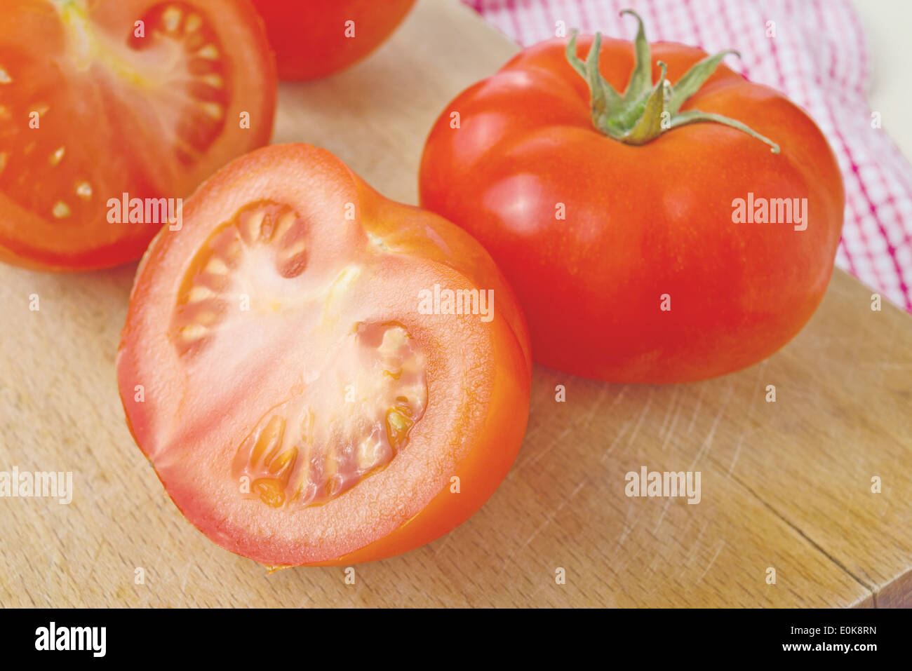 Pomodori freschi maturi con halfs sulla tavola di legno, gustose verdure biologiche per mangiare sano. Foto Stock