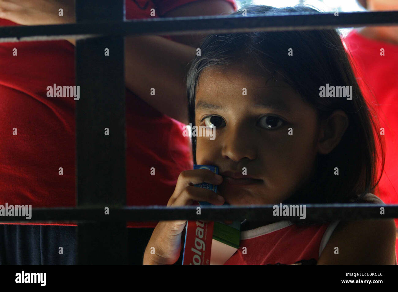 GUIMBA, Filippine-un locale ragazza filippina sguardi attraverso una finestra con la sua pasta dentifricia dopo aver ricevuto aiuti dentale forma servicemem Foto Stock