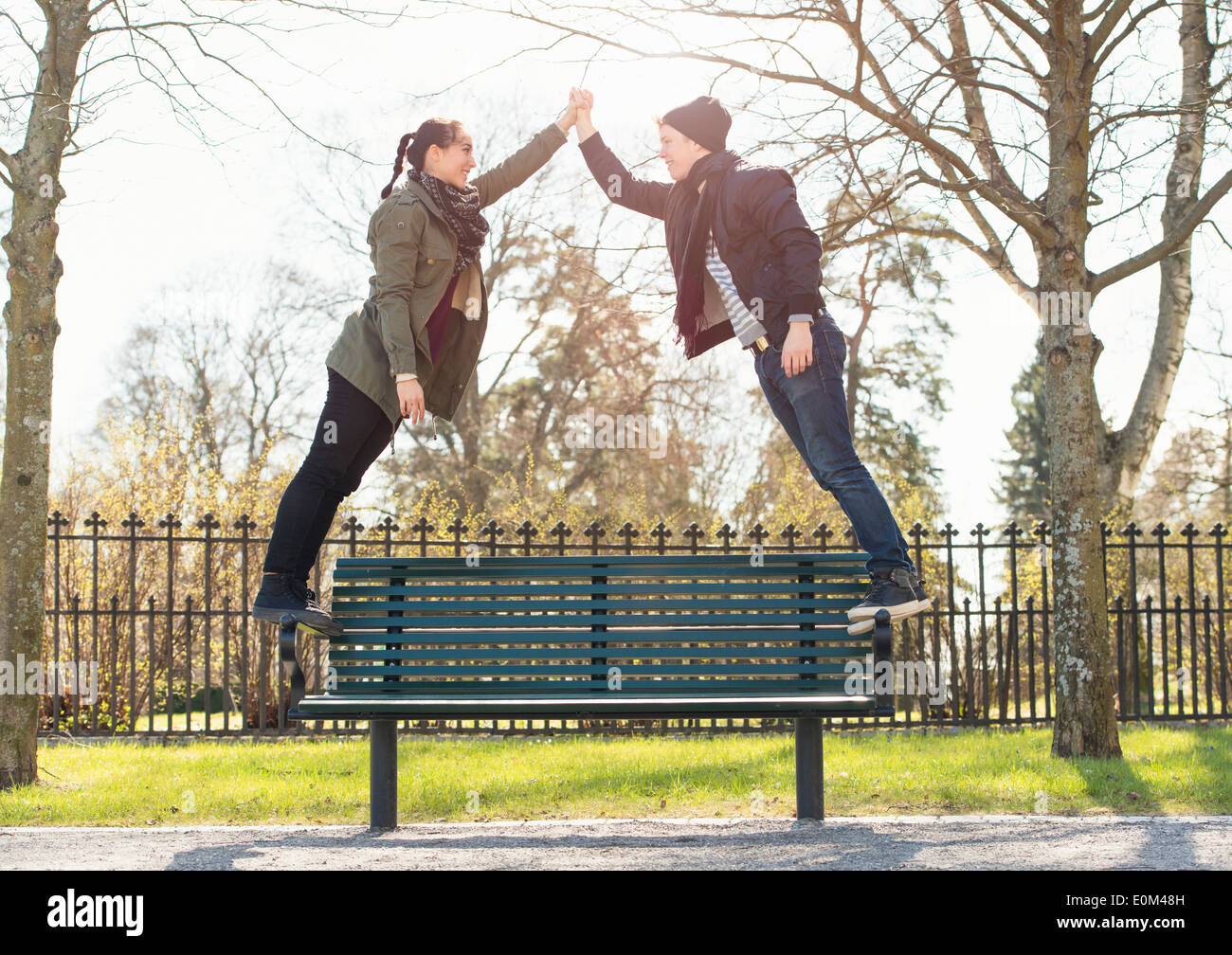 Dating coppia giovane in piedi su una panchina nel parco, tenendo le mani. Foto Stock