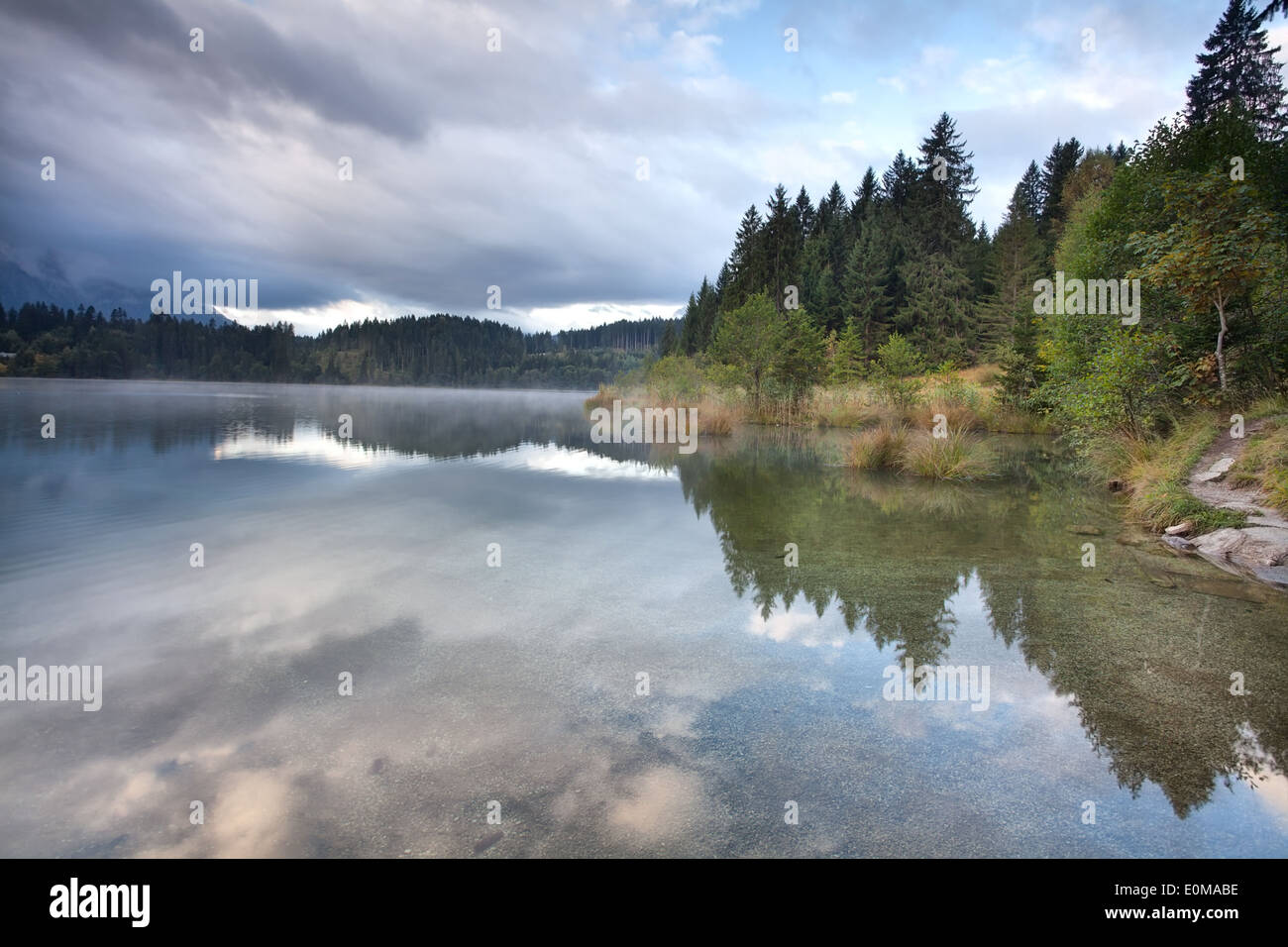 Foschia mattutina sul lago alpino nella foresta di conifere, Barmsee, Baviera, Germania Foto Stock