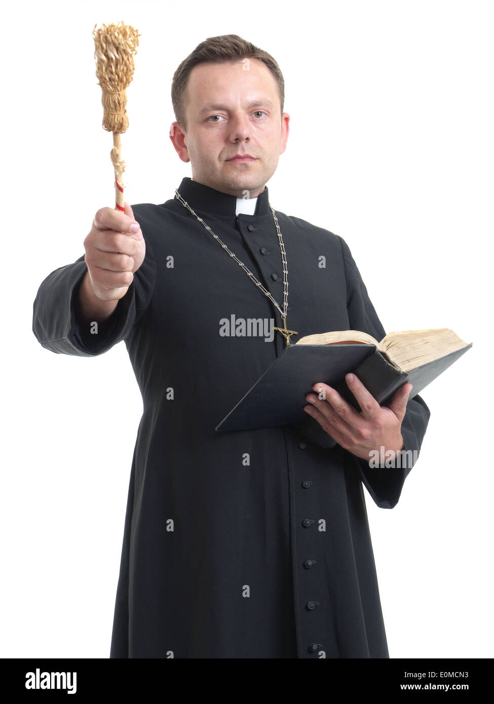 Sacerdote cattolico con aspergillum e Holly la Bibbia di eseguire esorcismi shot su bianco Foto Stock