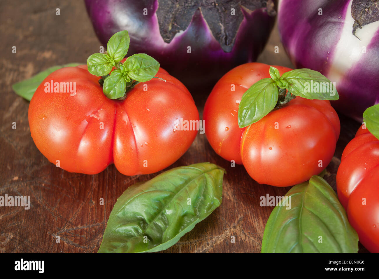 Melanzana pomodoro le foglie di basilico closeup zoom in legno Foto Stock