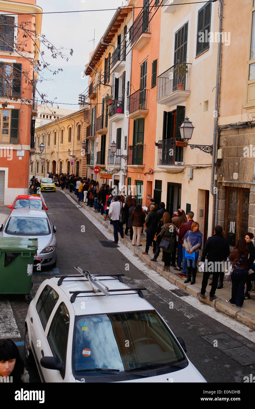 La gente in attesa al di fuori di una impresa che offre 120 posti di lavoro temporanei nell'isola di Maiorca, SPAGNA Foto Stock