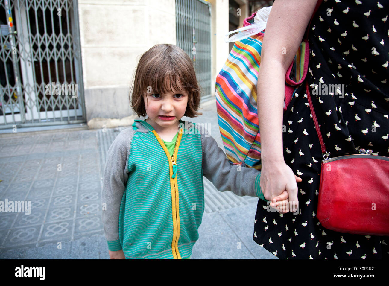 Cinque anni di vecchio ragazzo tenendo la sua madre la mano prima di attraversare la strada, Barcellona, Spagna Foto Stock