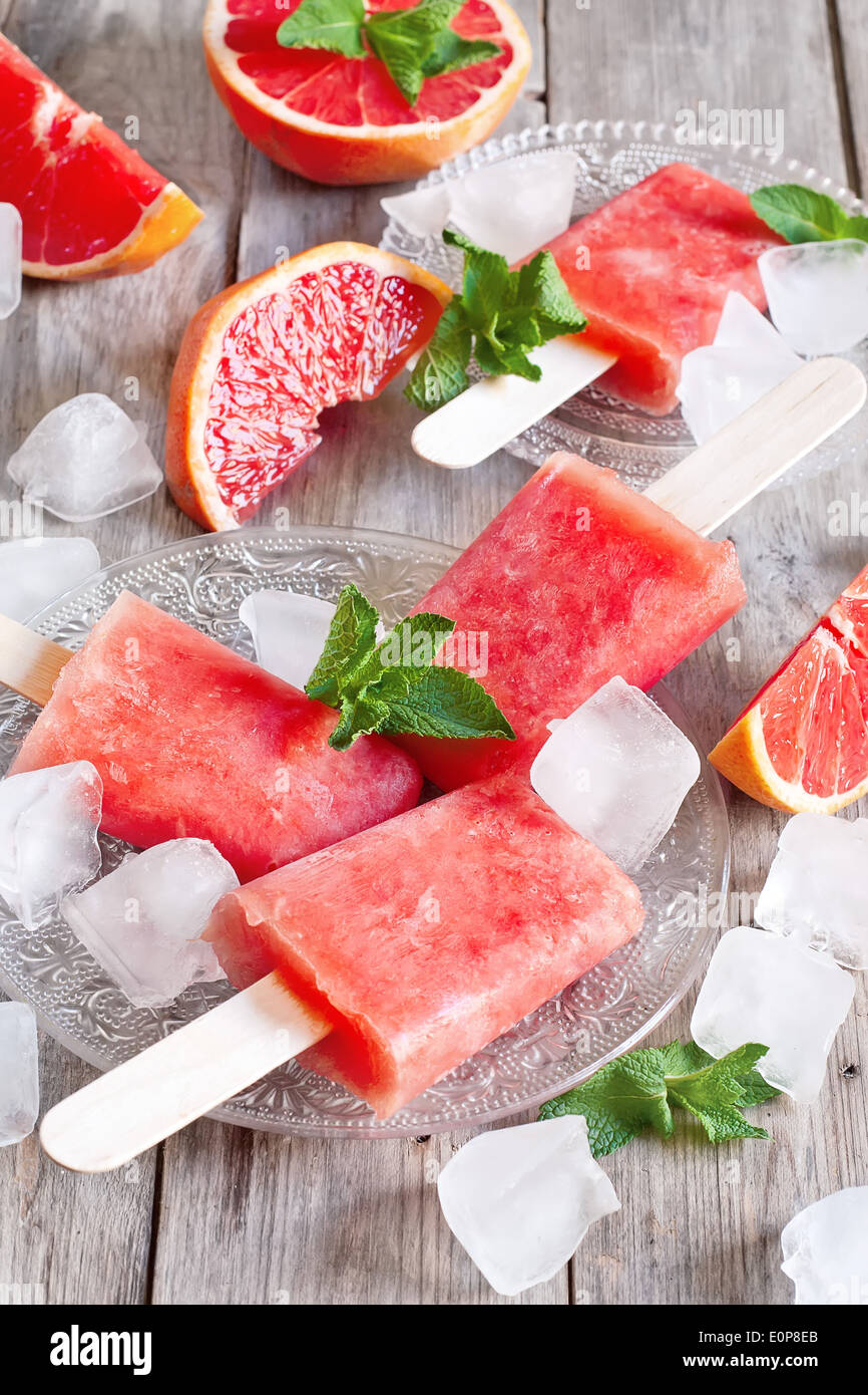 Pompelmo rosso popsicles fatti in casa con cubetti di ghiaccio. Messa a fuoco selettiva. Foto Stock