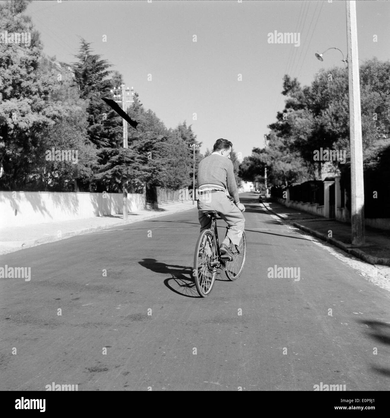 Un ciclista in bicicletta lungo una strada, una forma di trasporto comunemente usata sia per gli spostamenti che per le attività ricreative. Le biciclette offrono una modalità di viaggio ecologica ed efficiente. L'immagine mette in evidenza l'ambiente urbano e sottolinea il ruolo delle biciclette nel trasporto sostenibile. Foto Stock