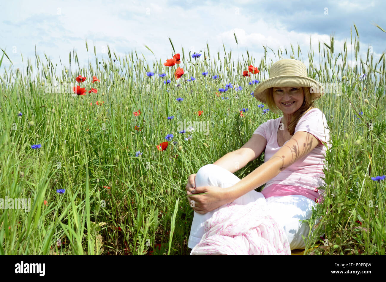 Donna con cappello seduti sul prato Foto Stock