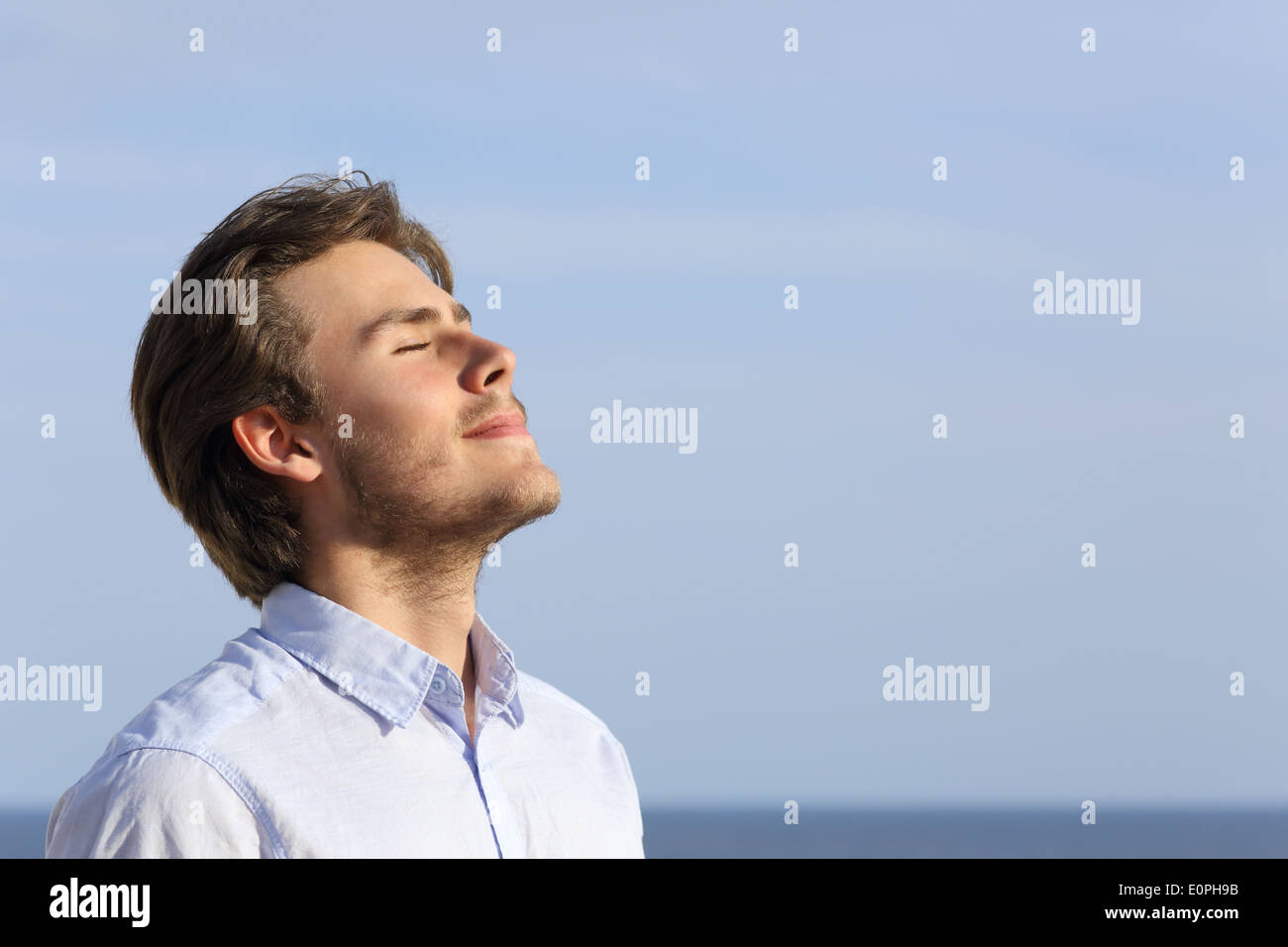 Felice giovane uomo respirazione profonda con l'orizzonte in background Foto Stock