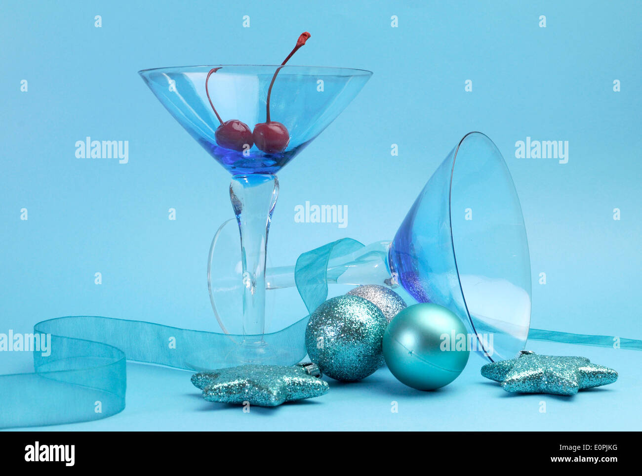 Lo spirito di festa blue martini cocktail con occhiali rossi ciliegie al maraschino e baubles di Natale. Foto Stock