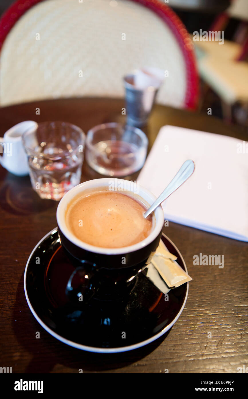 Primo piano della tazza di caffè espresso con cucchiaio in metallo su legno tabella cafe con posacenere in background Foto Stock