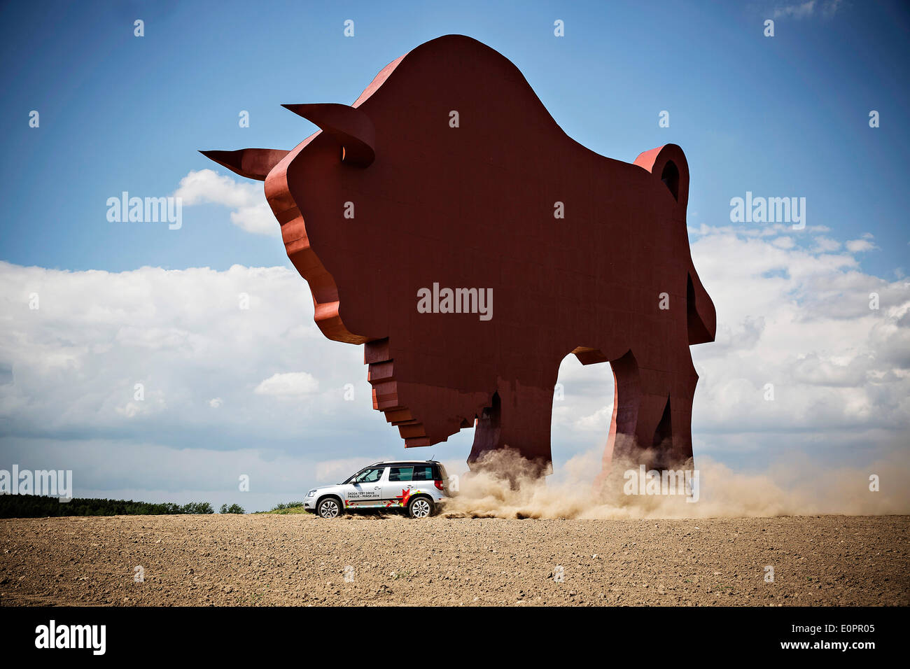 Un SUV con i giornalisti scorre attraverso un campo per visualizzare una gigantesca statua di bielorusso simbolo nazionale, il Bisonte Europeo, su una autostrada che conduce a Minsk, Bielorussia, Sabato, Maggio 10th, 2014. Le autostrade in Bielorussia non conformi con West norme europee. Western Foto Stock