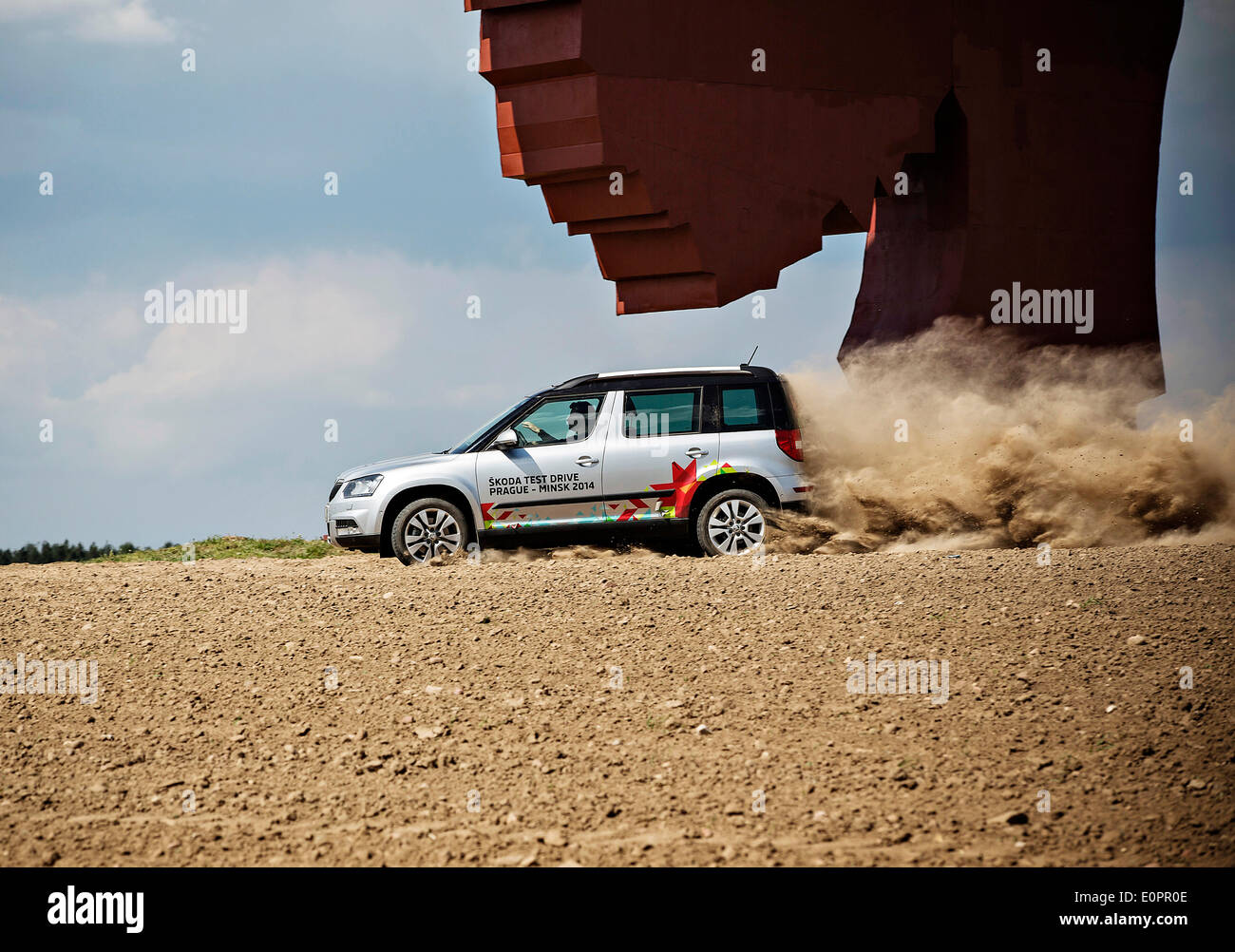 Un SUV con i giornalisti scorre attraverso un campo per visualizzare una gigantesca statua di bielorusso simbolo nazionale, il Bisonte Europeo, su una autostrada che conduce a Minsk, Bielorussia, Sabato, Maggio 10th, 2014. Le autostrade in Bielorussia non conformi con West norme europee. Western Foto Stock