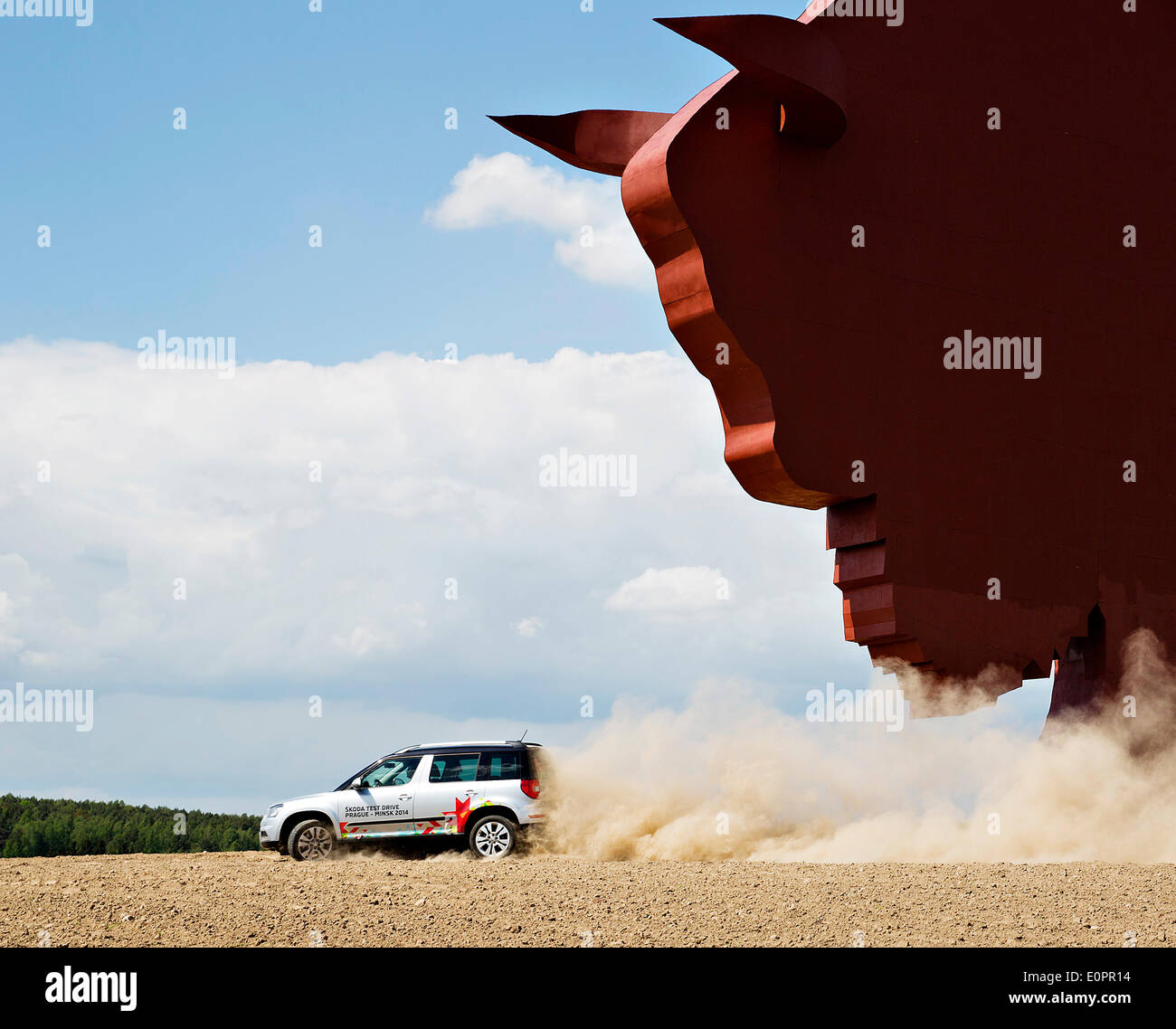 Un SUV con i giornalisti scorre attraverso un campo per visualizzare una gigantesca statua di bielorusso simbolo nazionale, il Bisonte Europeo, su una autostrada che conduce a Minsk, Bielorussia, Sabato, Maggio 10th, 2014. Le autostrade in Bielorussia non conformi con West norme europee. Western Foto Stock