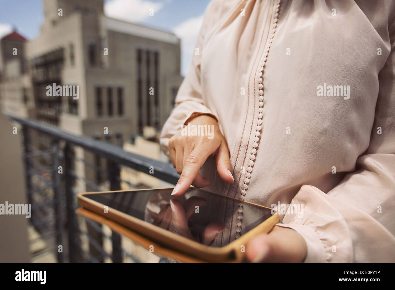 Chiudere l immagine della giovane donna in piedi sul balcone con tavoletta digitale. Immagine ritagliata del lavoro femminile sul computer tablet. Foto Stock