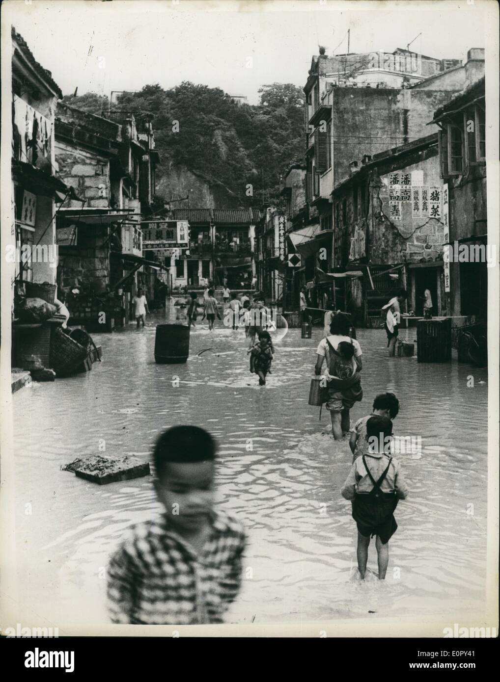 05 maggio 1957 - La scena in hongkong dopo precipitazione più pesante mai quarantanove ucciso-cinque mila senzatetto: le piogge è venuto a Colonia di Hong Kong di recente - ed è sceso per ora dopo ora per due giorni senza una pausa. In sessanta ore più di venti centimetri di pioggia caduta - la più pesante mai registrata in Hong Kong. Le tempeste che hanno accompagnato la pioggia è costato la vita a 49 persone - e reso un altro 5.000 senzatetto. La foto mostra la scena come persone wade lungo una strada allagata nel rifugiato cinese abitato di Hong kong Foto Stock