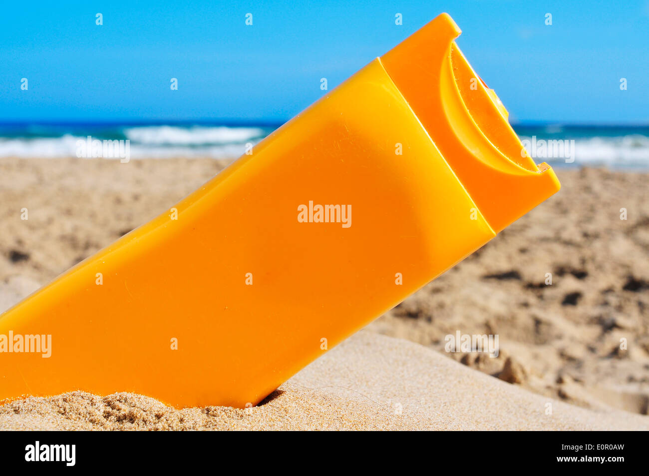 Una bottiglia di sunscreen sulla sabbia di una spiaggia Foto Stock