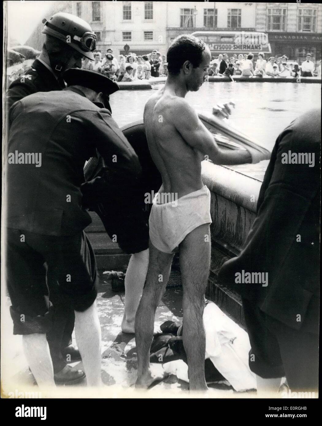 Agosto 08, 1959 - Sansation in Piazza Trafalgae. Un uomo è andato a bagnarsi.: un uomo di colore ha creato una sensazione in Trafalgar Square oggi - quando ha spogliato - e se ne andò per un 'ip'. La polizia aveva di gettarvi in acqua per forza fuori di lui. La foto mostra la polizia ottenere l'uomo vestito di se stesso dopo il suo 'ip' con le fontane di oggi. Foto Stock