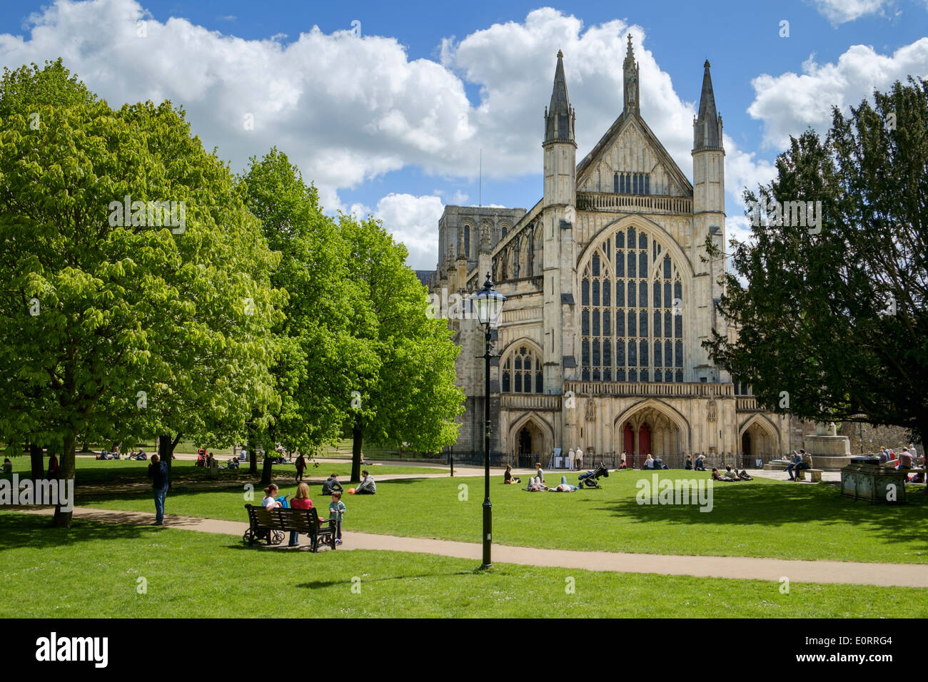 La Cattedrale di Winchester, Hampshire, Inghilterra, Regno Unito - con persone rilassante nel parco Foto Stock