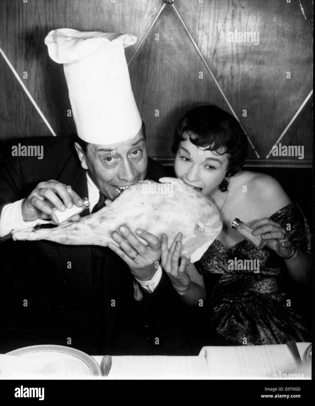 Attore Fernandel e donna mangiare gigantesco pezzo di carne Foto Stock